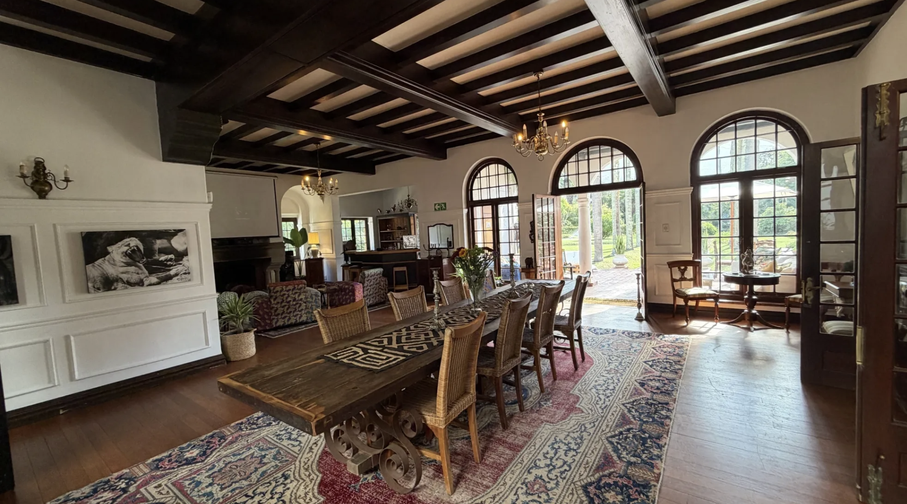 The dining hall at Glenhof Manor — long wooden table beneath dark beams and arched windows