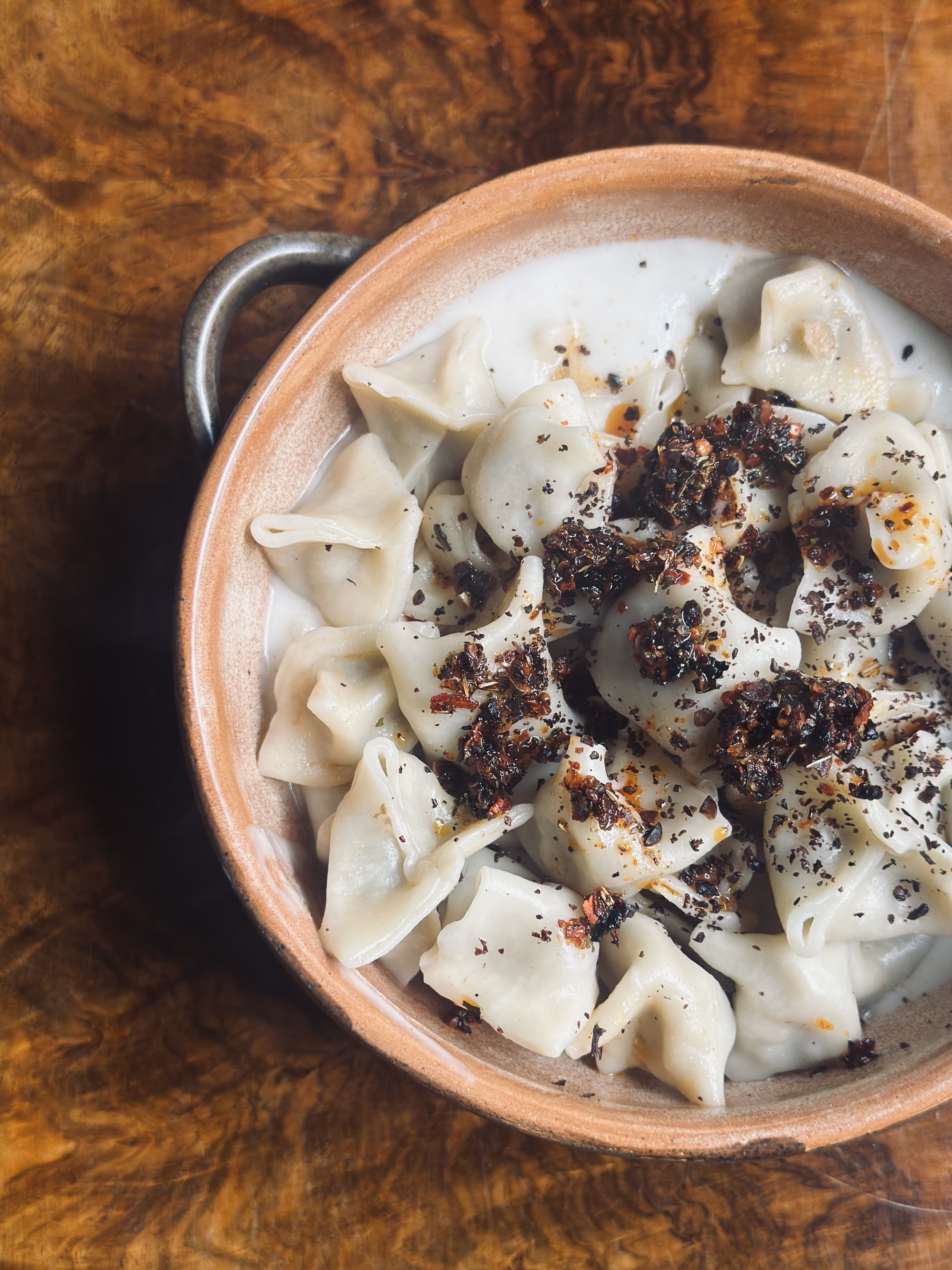 Vegan mantı dumplings in a terracotta bowl with Aleppo-spiced butter and yoghurt